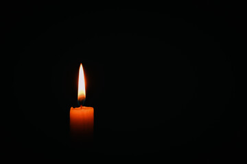 Candle flame on black background. Single lit candle with quite flame. Dramatic burning candle flame on a black background with copy space