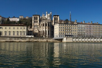 Fototapeta premium Impressive basilica Notre Dame de Fourviere overlooking the beautiful cathedral Saint Jean Baptiste and all reflected in the river Saone.