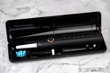 Modern black sonic or electric toothbrush in travel case. Concept of professional oral care and healthy teeth by using sonic smart toothbrush. Minimal design
