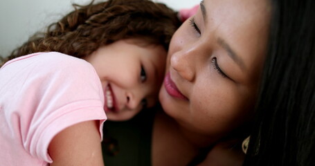 Asian mother cuddling with little daughter in arms, love and affection
