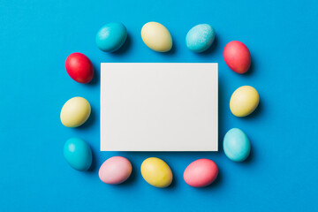 round frame multicolored Easter eggs with white blank paper on a brown background, close-up, space for text, blank for design, selective focus, tinted image