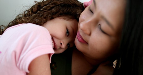Asian mother cuddling with little daughter in arms, love and affection