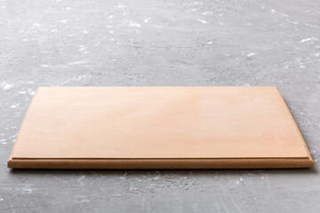 Fototapeta premium Perspective view of wooden cutting board on cement background. Empty space for your design