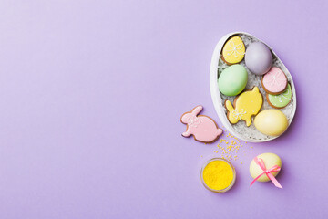 Colorful easter cookies in basket with Multi colors Easter eggs on colored background . Pastel color Easter eggs. holiday concept with copy space