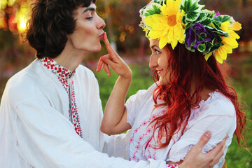 Wedding in traditional costumes of Slavic peoples. People in Ukrainian, Polish, Slovak, Hungarian national clothes. A girl with a wreath on her head. Happy couple in nature - obrazy, fototapety, plakaty