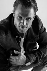 handsome sexy male model alone in the studio, a man with beautiful athletic muscles, jeans and a white t-shirt