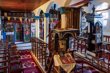 Agios Athanasios Greek empty Christian Orthodox church interior. Inside religious place with worship icons and chairs for faithful.