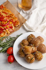 Blurred image of a baked potato, hot sandwiches on parchment, a drink on a gray table. View from above.