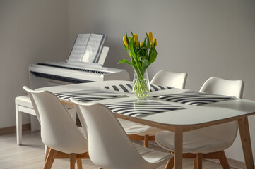 Cozy white family table with vase and fresh yellow tulips