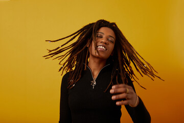 Studio portrait of woman with dreadlocks against yellow background