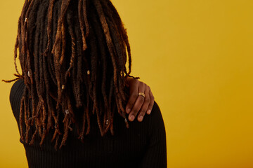 Rear view of woman with dreadlocks against yellow background © Cultura Creative