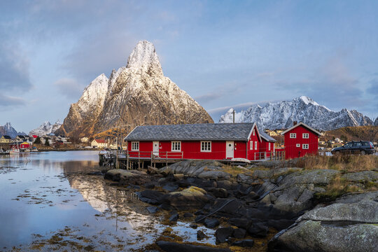 Small coastal village with cottages in bay near snowy mountains - Powered by Adobe