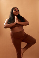 Studio shot of smiling plus size woman in tree pose