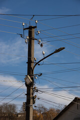 Electric wires hanging on a pole with a lighting lamp photographed from below on a background of...