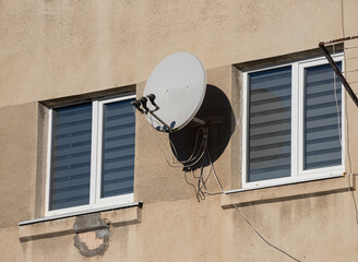 TV satellite parabolic antenna attached to the wall of the house