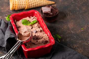 Homemade chocolate ice cream in a bowl with chocolate and mint on the dark table, copy space for text
