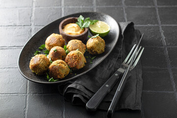 Chickpea falafel with sauce on black plate and black background