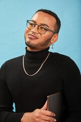 Studio portrait of smiling queer man with laptop