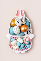 Happy Easter concept. Cute plate in the shape of a bunny with  Easter eggs and candy on beige...