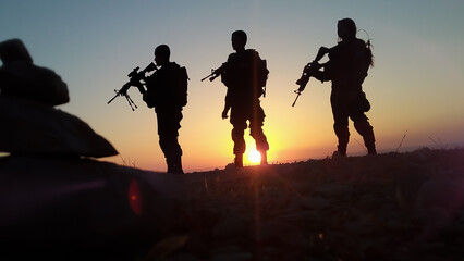 Silhouette of soldiers with weapons at sunset. High quality photo
