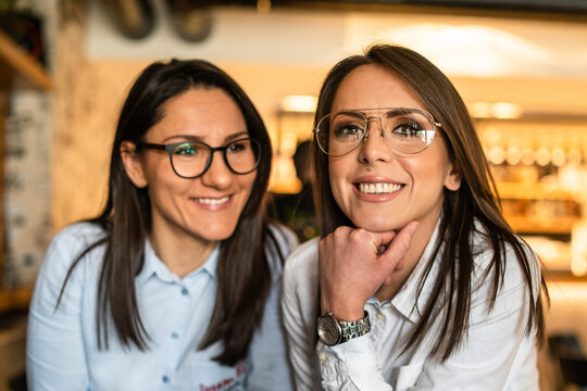 Front view of two women adult female friends wearing eyeglasses happy smiling