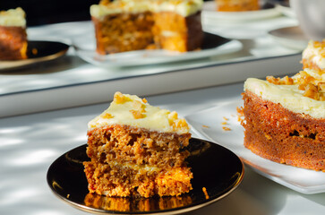 Sliced carrot cake filled and topped with cream cheese buttercream and decorated with walnuts