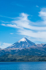 Fototapeta premium Top of volcano peak mountain with snow under the blue sky with grass field and steppes. 