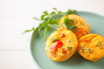 Egg muffins ( bites) and parsley leaves  in a plate on a gray background.