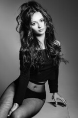 Pretty girl with sexy figure, long brown glancy hair posing at studio.
