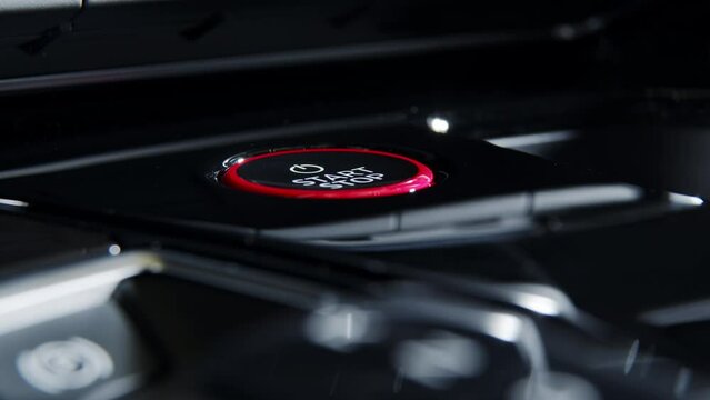 a woman's hand starts an electric car by placing her finger on the start button in her electric car. luxury car interior. Close-up. Side view
