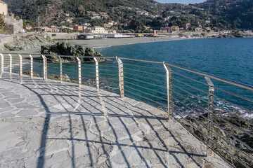 shadows and reflections of railing at Bonassola beach walkway, Italy