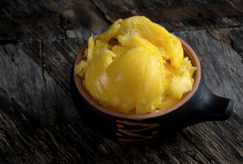 Ghee in a cup on an old wooden table.