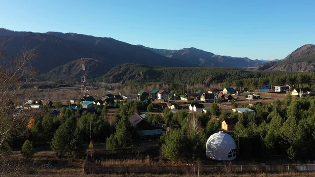 Geo dome and houses in Chemal village in Altai mountains, aerial view, tourist destination of Russia