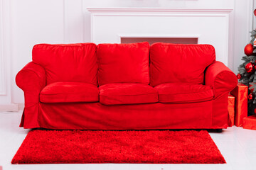 Decorated Christmas interior with red sofa, red carpet, white walls, fireplace and big Christmas tree. decorated room for celebrating of New Year