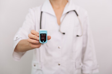 Pulse oximeter with hand of doctor isolated on white. Measuring oxygen saturation, pulse rate and oxygen levels. The concept of portable digital device to measure person's oxygen saturation.