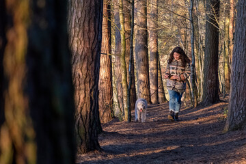Young woman walking dog in forest