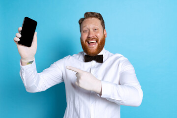 Studio shot of sport referee wearing white shirt and butterfly tie isolated on blue studio...