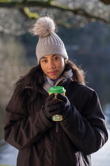 Portrait of smiling young woman holding insulated cup