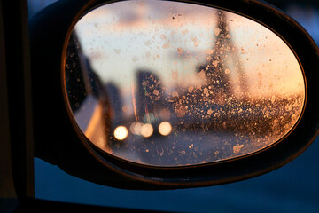 Focus on dirty automotive mirror car with sunlight on road bridge, on the move with blurry background. Close up shot of charming sunset reflection in side rear-view mirror on a car. © Elizabeth