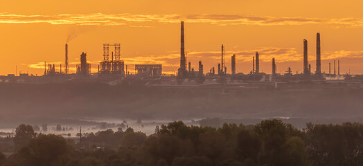 Fototapeta premium Industrial landscape with silhouettes of factory chimneys at dawn