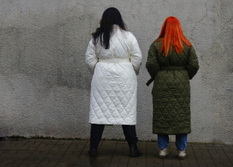 Obraz na płótnie Canvas Two plus size women stand with their backs to the camera in coats.