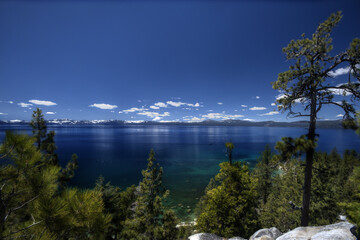 An astonishing view of Lake Tahoe with puffy clouds and snow on mountains