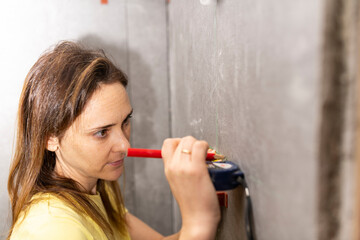 woman taking measurements or drawing points with a meter and a level in a work or renovation in a flat or house