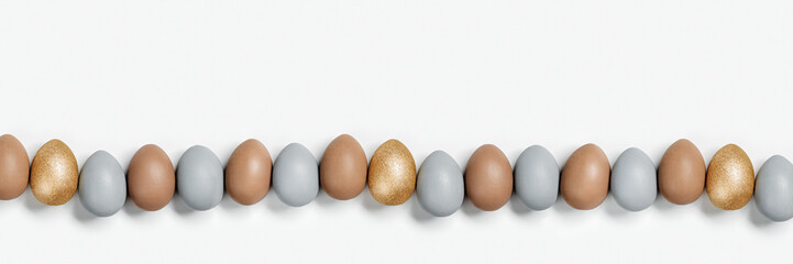 Painted Easter eggs gray, beige and golden colored in row on white background with copy space. Chicken egg natural pastel shades. Easter holiday food, minimal design aesthetic wide banner