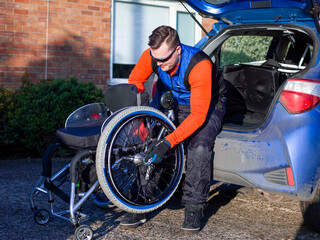 Disabled man setting up handcycle at car