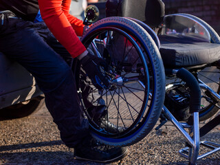 Low section of disabled man setting up handcycle at car - obrazy, fototapety, plakaty