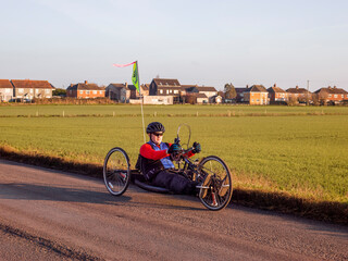Disabled man riding handcycle on country road