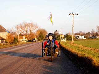 Disabled man riding handcycle on country road