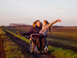 Happy woman and man on wheelchair in field - obrazy, fototapety, plakaty
