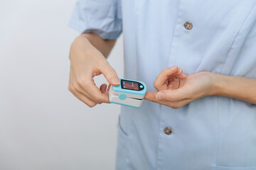 Pulse oximeter with hand of doctor isolated on white. Measuring oxygen saturation, pulse rate and oxygen levels. The concept of portable digital device to measure person's oxygen saturation.